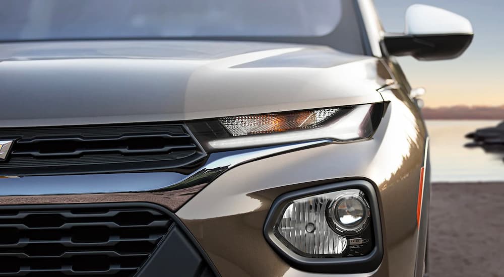 A close up of the front of a brown 2022 Chevy Trailblazer shows the driver's side headlight and grille.