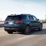 A blue 2022 Chevy Traverse is shown from the rear driving on a highway.