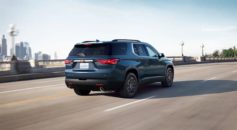 A blue 2022 Chevy Traverse is shown from the rear driving on a highway.
