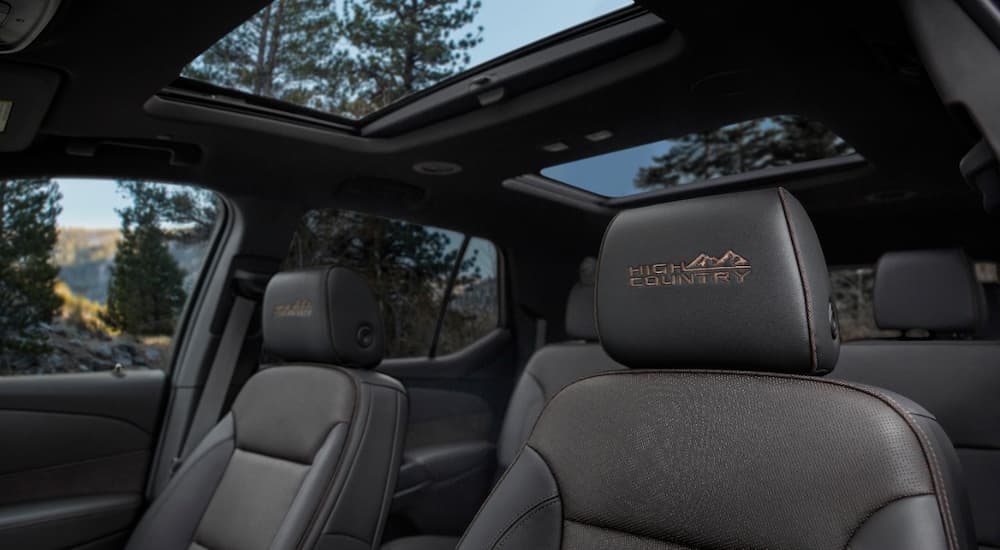The black and brown accented interior of a 2022 Chevy Traverse High Country shows the front seats and moon roof.