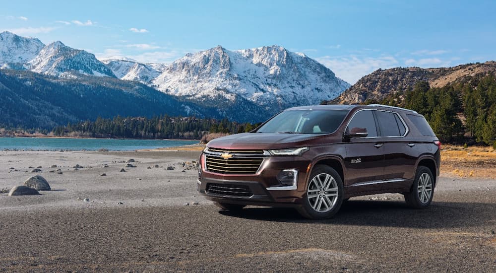 A maroon 2022 Chevy Traverse High Country is shown from the side parked with a mountain view.