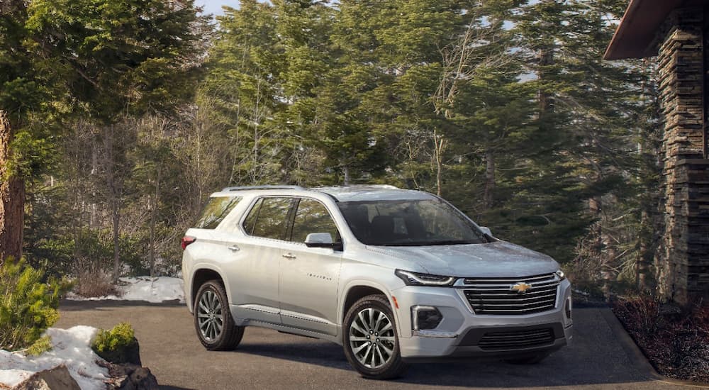 A silver 2022 Chevy Traverse Premier is shown parked in a driveway outside of a family home.