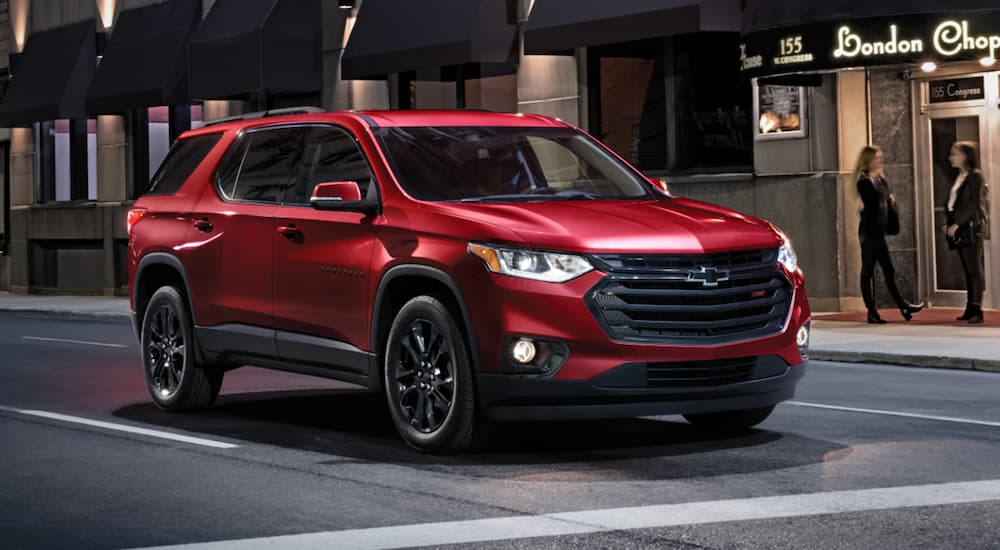 A red 2022 Chevy Traverse is shown stopped at a red light in a city.