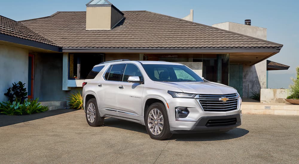 A silver 2022 Chevy Traverse is shown at an angle parked in front of a family home.