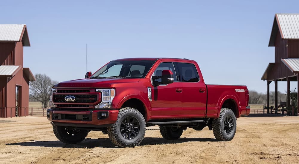 A red Ford 2022 F-250 Lariat is shown from the side parked at a farm.