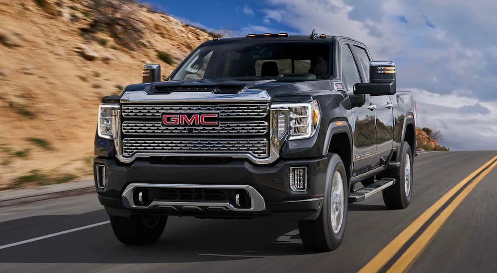 A black 2022 GMC Sierra 2500 HD Denali is shown from the front driving on a highway during a 2022 F-250 vs 2022 GMC Sierra 2500 HD comparison.