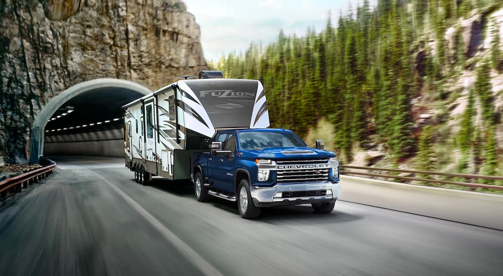 "A blue Chevy Silverado 2500HD is shown towing a camper during a 2022 Ford F-250 vs 2022 Chevy Silverado 2500 HD comparison.