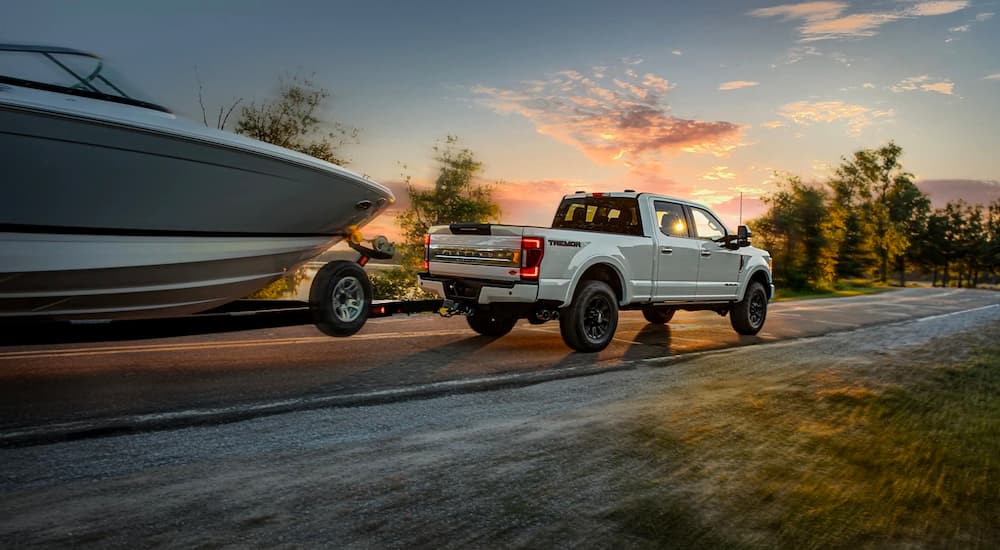A white Ford F-250 Platinum Tremor is shown from a rear angle towing a boat.