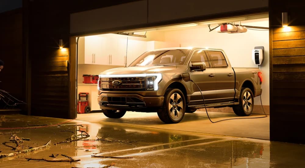 A grey 2022 Ford Lightning is shown charging in a garage after winning a 2022 Ford Lightning vs 2022 Tesla Cybertruck comparison.