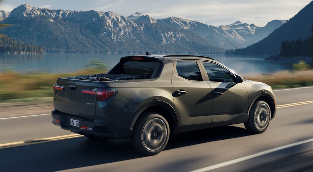 A green 2022 Hyundai Santa Cruz is shown from the side driving past a lake.