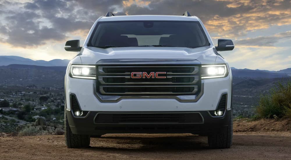 A white 2022 GMC Acadia is shown from the front parked in front of a mountain range.