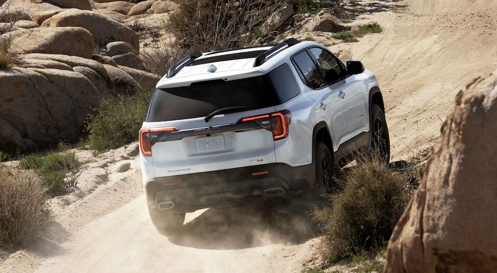 A white 2022 GMC Acadia is shown from the rear off-roading in the desert.
