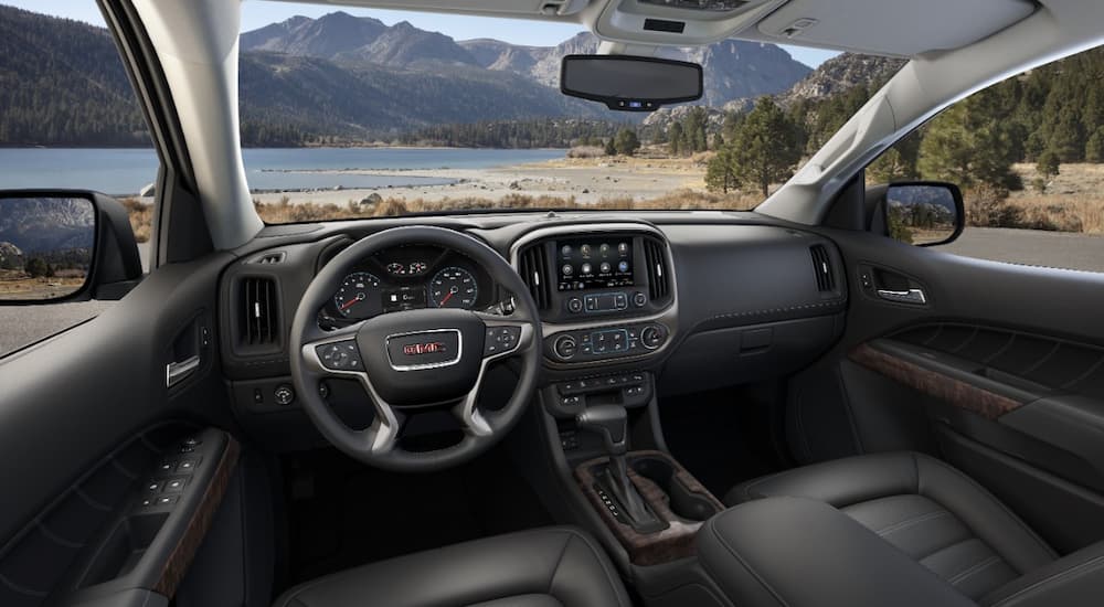 The black and silver accented interior of a 2022 GMC Canyon Denali shows the steering wheel and center console.