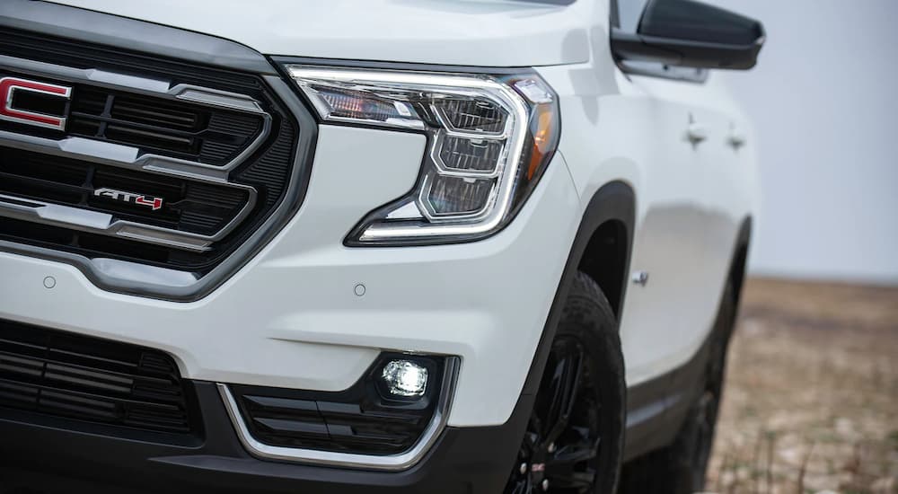 A close up of the front of a white 2022 GMC Terrain AT4 shows the driver's side headlight and grille.