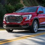 A red 2022 GMC Terrain SLT is shown from an angle driving down an empty road.