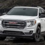 A white 2022 GMC Terrain is shown from the front off-roading through the mud.