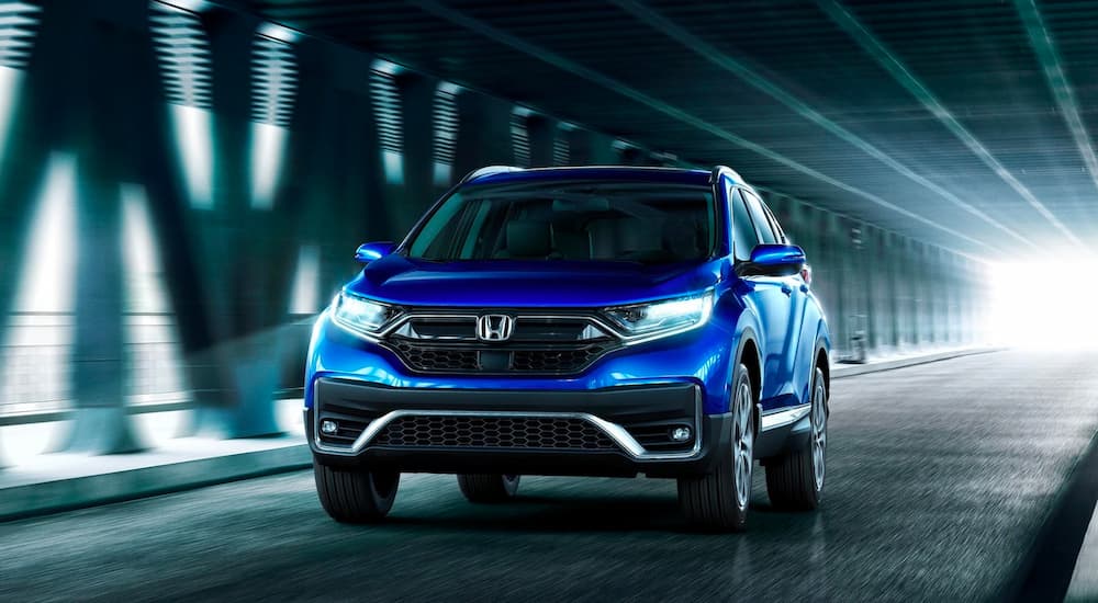 A blue 2022 Honda CR-V Touring is shown from the front driving through a tunnel.