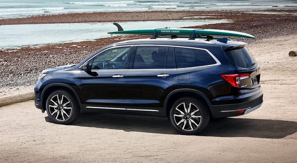 A blue 2022 Honda Pilot Elite is shown from the side parked at a beach.