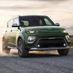 A green 2022 Kia Soul is shown driving on a dusty mountain road after leaving a Kia Soul dealer.