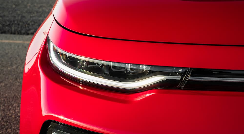 A close up shows the passenger side headlight of a red 2022 Kia Soul.