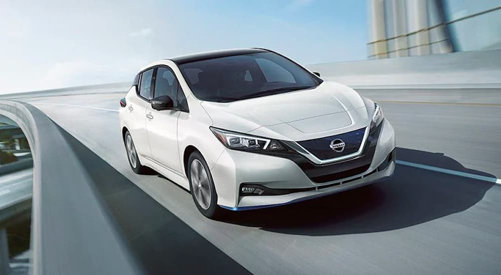 A white 2022 Nissan LEAF is shown driving over a bridge.
