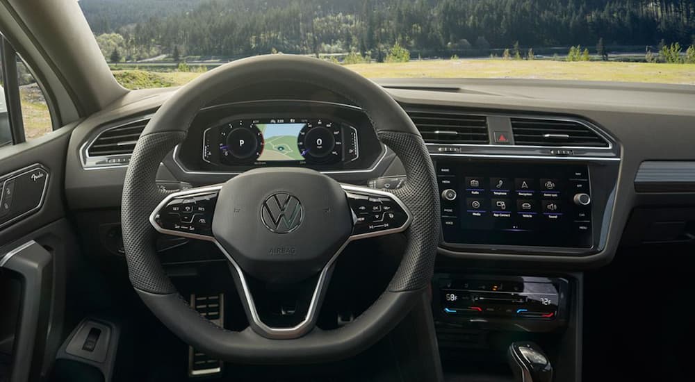 The grey interior of a 2022 Volkswagen Tiguan shows the steering wheel and infotainment screen.