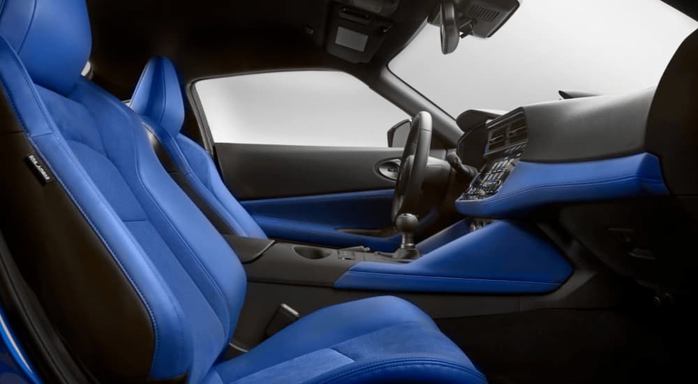 The blue and black interior of a 2023 Nissan Z is shows the front seats, shifter, and steering wheel.