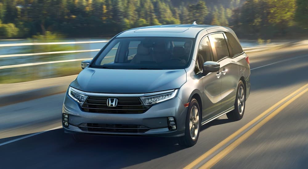 A silver 2021 Honda Odyssey Elite is shown driving on a road after looking at the best used cars for sale.