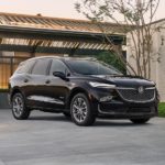 A black 2022 Buick Enclave is shown from the side parked in front of a modern house.