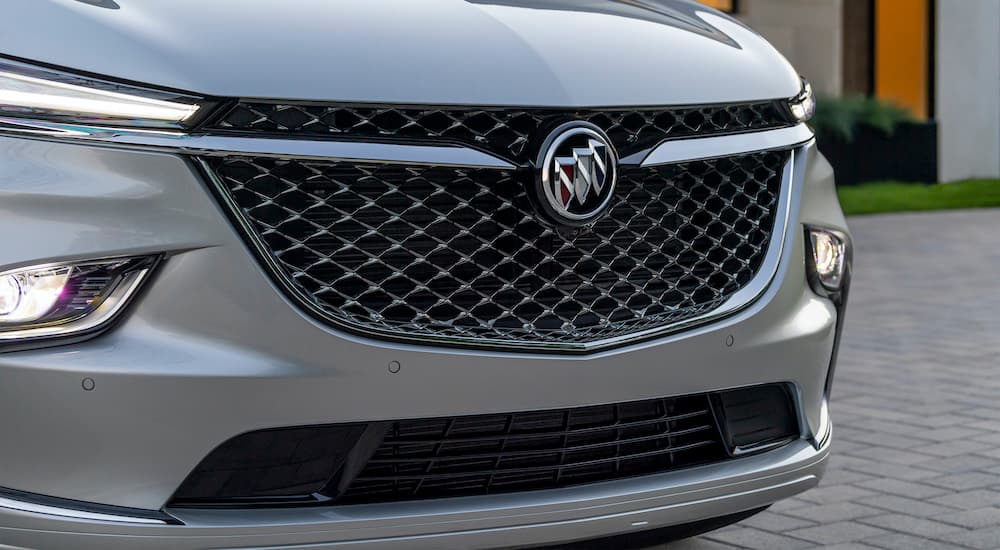 A silver 2022 Buick Enclave shows the grille in close up after leaving a Buick dealership. 