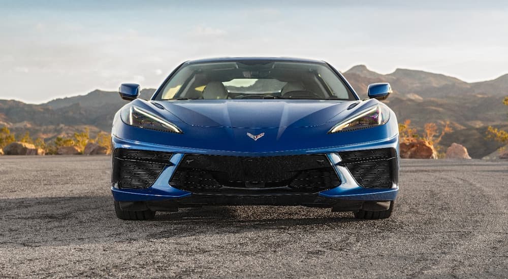 A blue 2022 Chevy Corvette Stingray is shown from the front parked on a desert road.