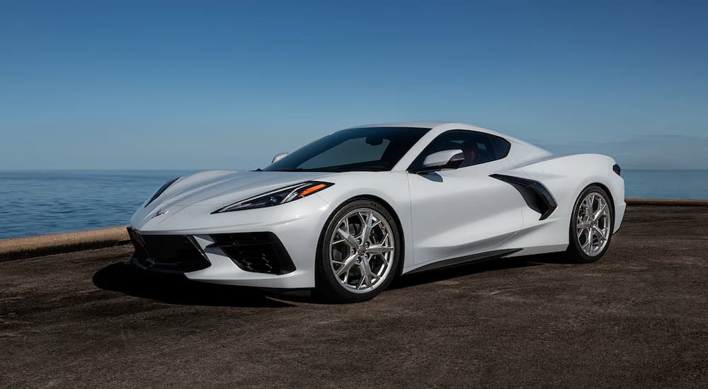 A white 2022 Chevy Corvette is shown parked at a Chevy dealer near the ocean.