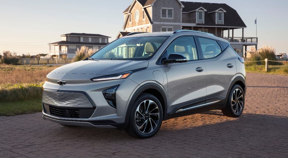A silver 2022 Chevy Bolt EUV is shown from an angle parked in a driveway in front of a home.