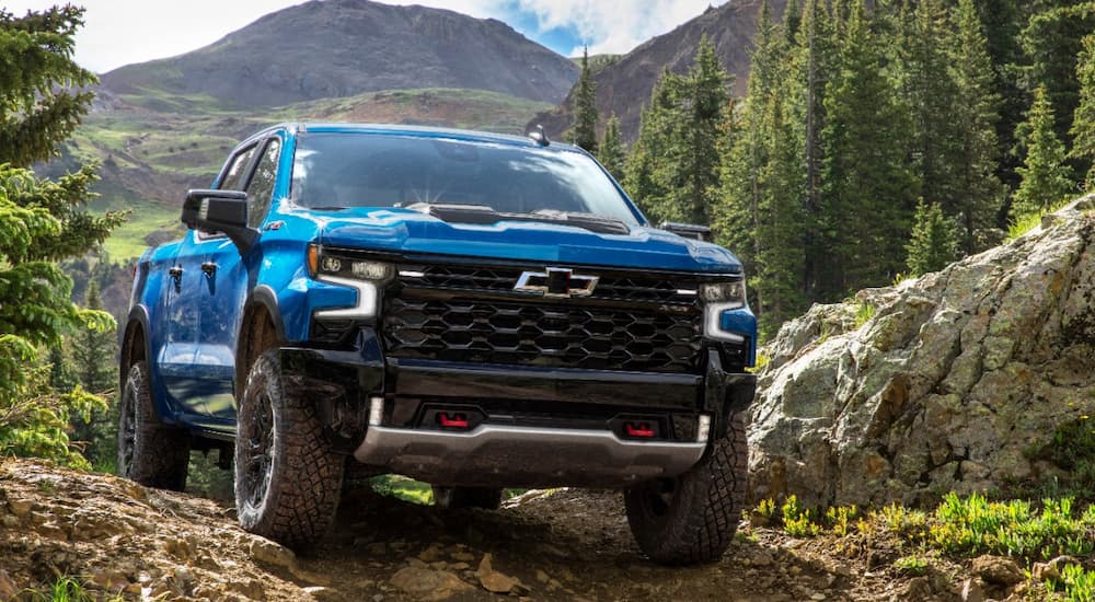 A blue 2022 Chevy Silverado ZR2 is shown from the front off-roading on a mountain trail.