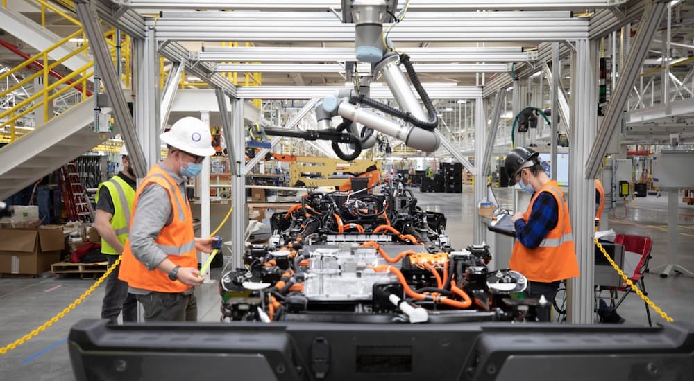 Two workers are shown on a Ford electric vehicle production line.