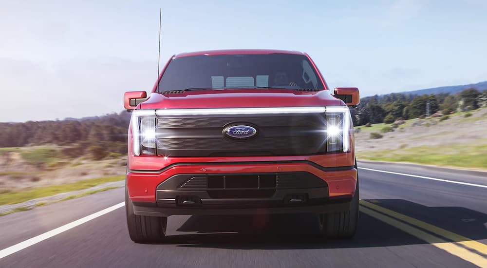 A red 2022 Ford Lightning F-150 is shown from the front driving on an open road.