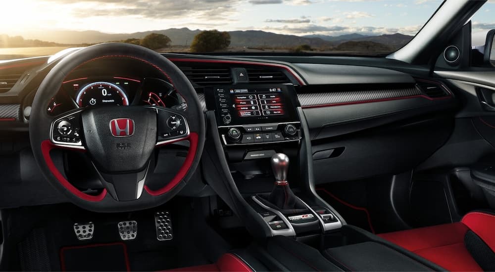 The black and red interior of a 2022 Honda Civic Type R shows the steering wheel and center console.