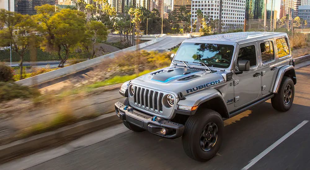A silver 2021 Jeep Wrangler 4xe is shown on a highway after leaving a Jeep dealership.
