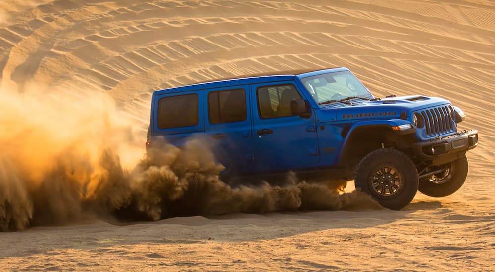 A blue 2021 Jeep Wrangler Rubicon 392 is shown from the side driving through a desert.