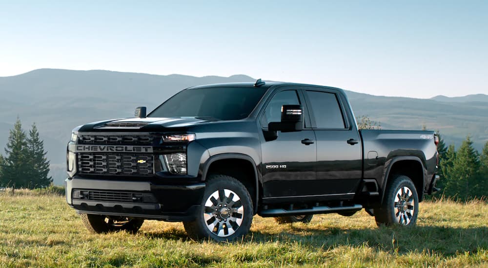 A black 2022 Chevy Silverado 2500 HD is shown from the side parked in a field.