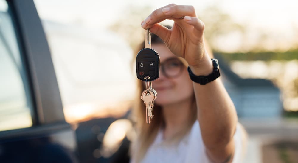 A woman is shown holding up a set of car keys.