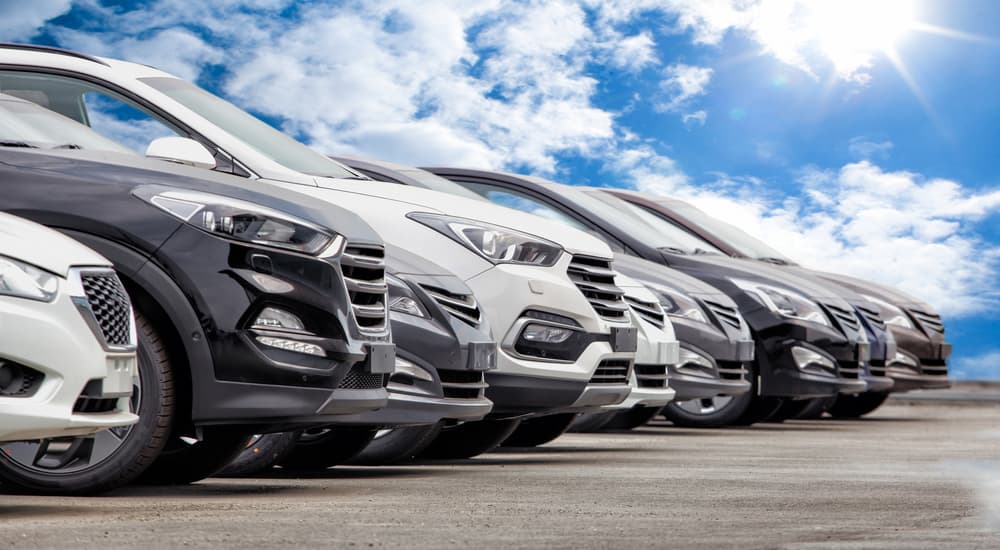 A line of used cars are shown at a used car dealership.