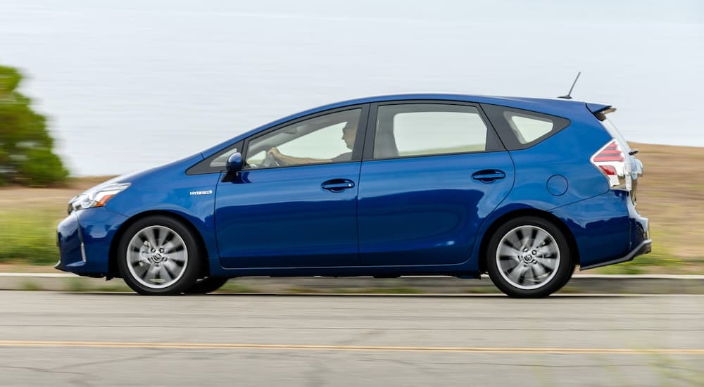 A blue 2016 Toyota Prius is shown from the side driving on a highway.