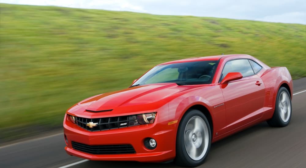 A red 2008 Chevy Camaro SS is shown driving down a road after leaving a used Chevy dealer.