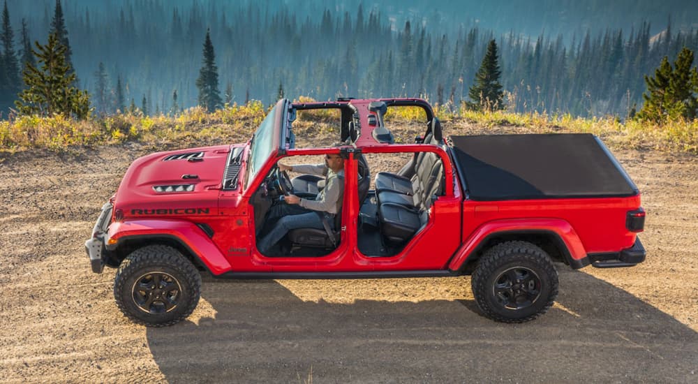A red 2020 Jeep Gladiator Rubicon is shown driving on a remote trail after leaving a used Jeep Gladiator dealer.