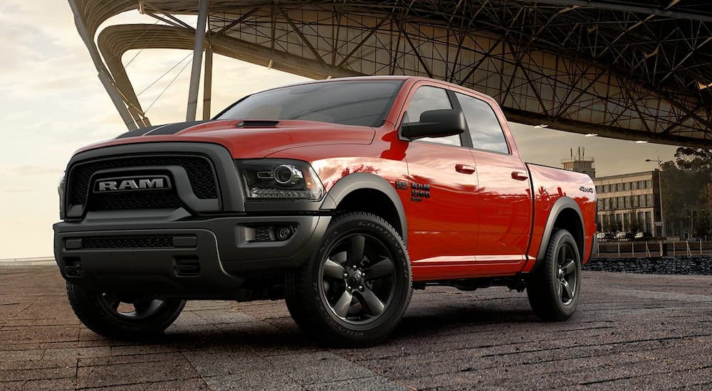 A red 2019 Ram 1500 Warlock is shown parked near a used truck dealer.