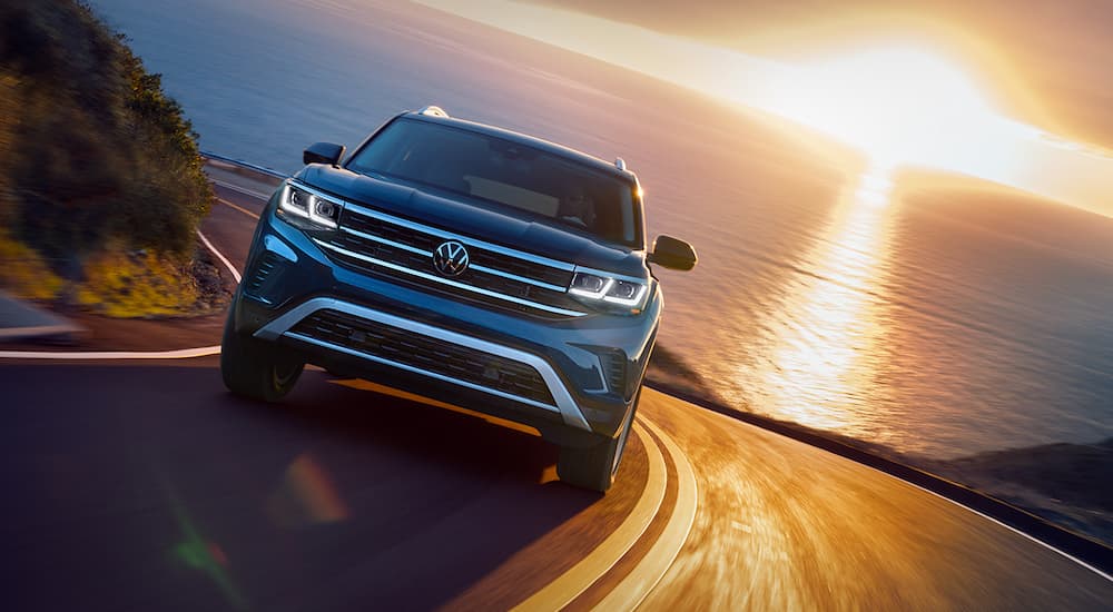 A blue 2021 Volkswagen Atlas SEL is shown driving away from the ocean after visiting a Volkswagen dealer.