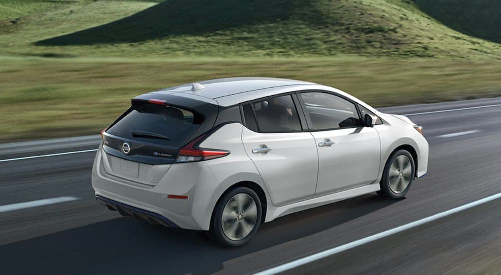 A white 2021 Nissan LEAF is shown from the side driving on a highway.