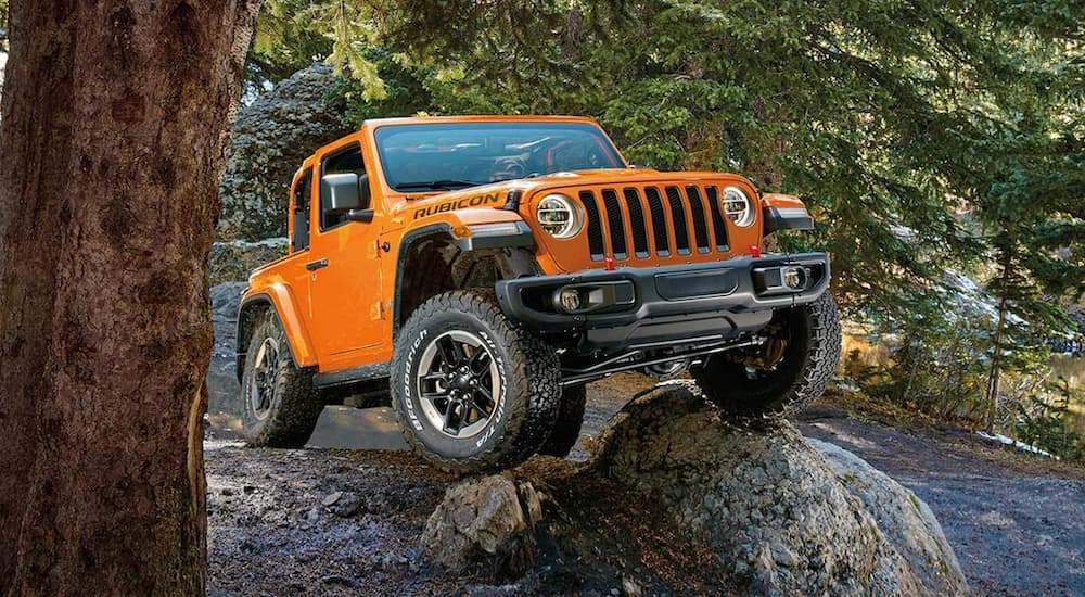 An orange 2019 Jeep Wrangler is shown parked on a rock after looking at a used Jeep Wrangler for sale.