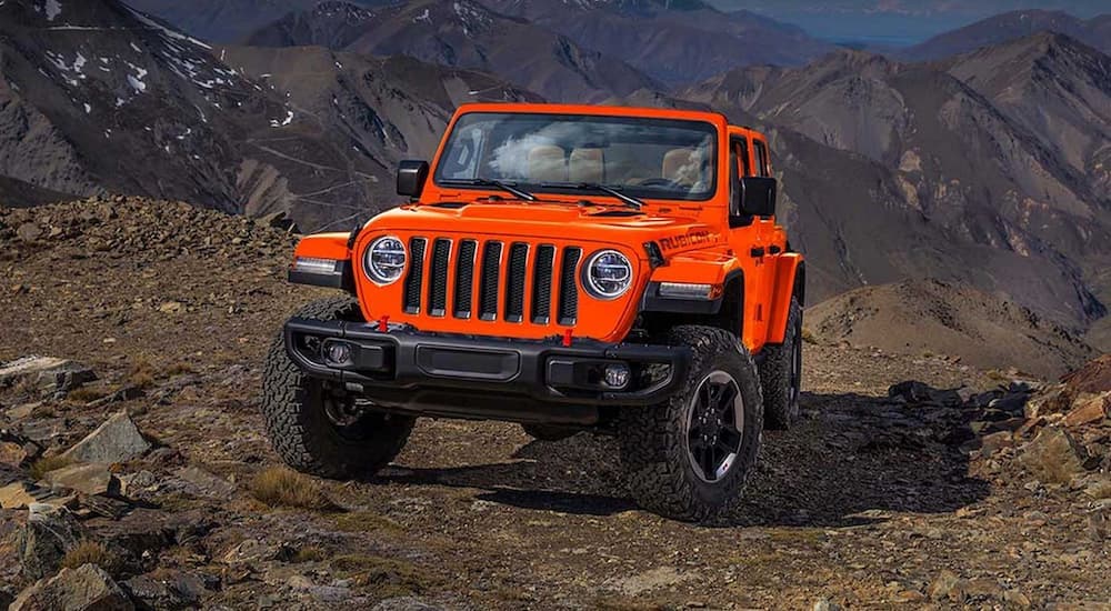 An orange 2019 Jeep Wrangler is shown from the front parked in the mountains after looking at a used Jeep Wrangler for sale.